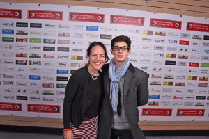Zwei Personen posieren lächelnd vor einer Wand mit vielen Sponsorlogos und Vereinswappen als Fotokulisse.