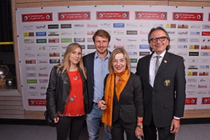 Vier Personen stehen vor einer Sponsorwand, lächeln in die Kamera und präsentieren den Anlass gemeinsam.