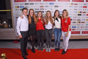 Gruppe von sechs Personen steht eng posierend vor einer Sponsorwand; Requisit zum Einstellen auf einer Veranstaltung.