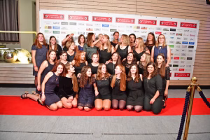 Gruppenfoto: Mehrere Frauen posieren vor einer Sponsorentafel in Sporthalle, auf rotem Teppich, mit Blick in die Kamera.