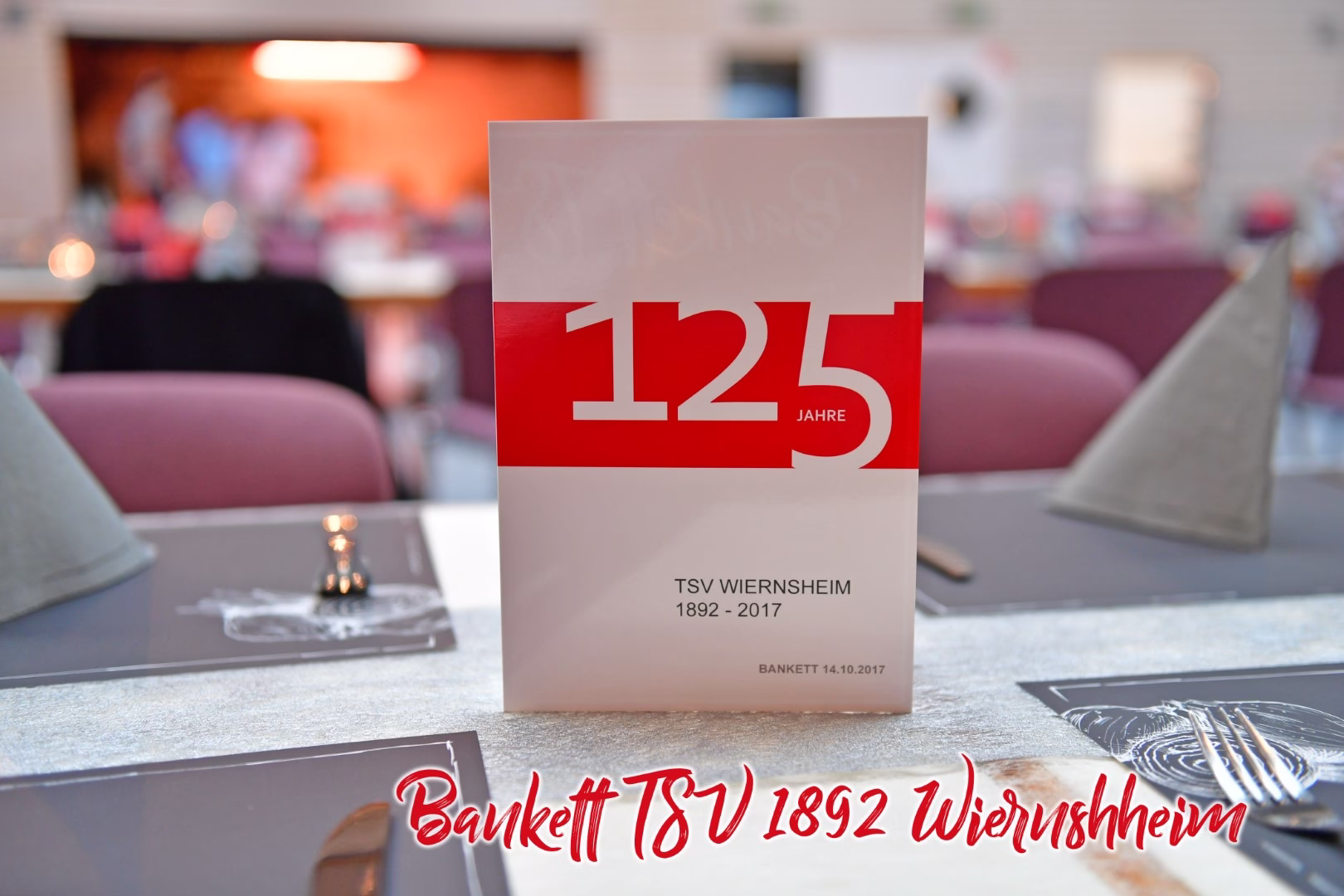 Stehende Jubiläums-Karte mit rotem „125“ und „JAHRE“, vor gedecktem Tisch mit Deko und unscharfem Hintergrund zur Begrüßung.