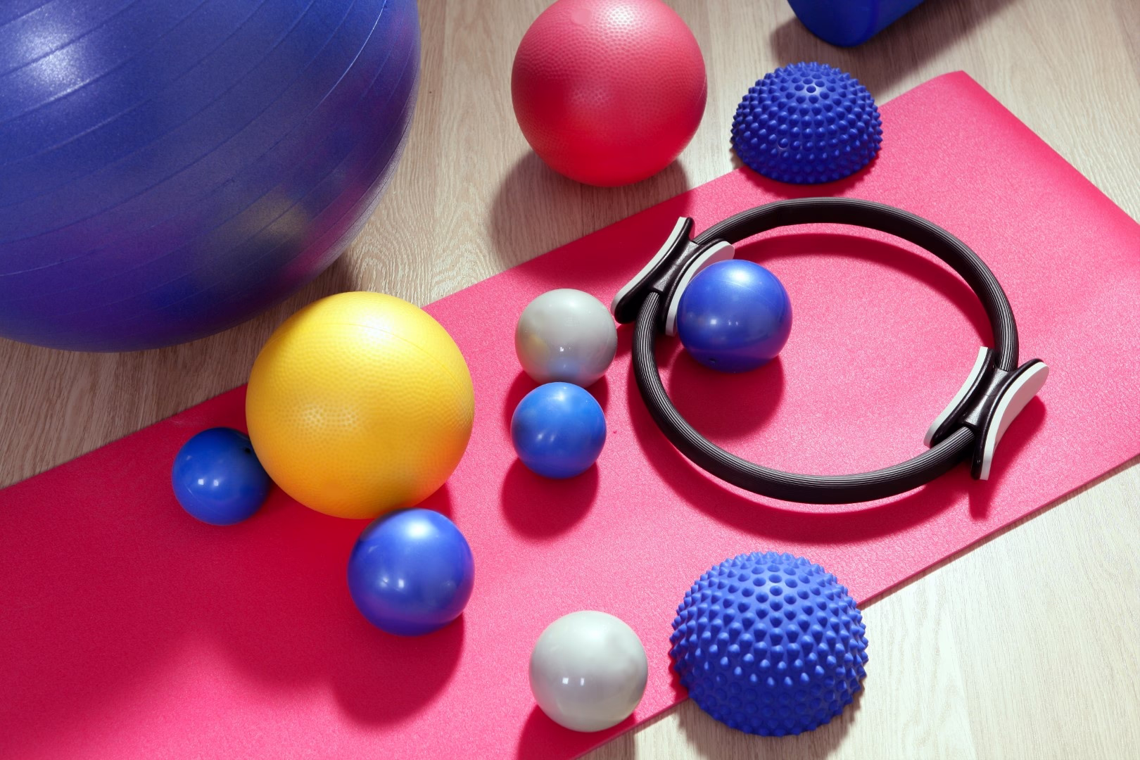 Gymnastik-Set: pinke Yogamatte mit Balance-Ring, großen und kleinen Kugeln sowie Massageball; dient Stabilitäts- und Muskeltraining.