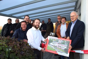 Gruppe steht auf einer Terrasse unter Überdachung, hält ein großes Dankesplakat als Blickfang.