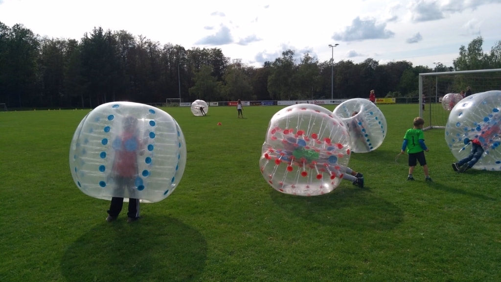 Ferienerlebnistag beim TSV Wiernsheim 14 Drei transparente Zorb-Bälle mit Kindern auf einem Rasenfeld, zur Unterhaltung und zum sicheren Rollen/Probieren im Freien.