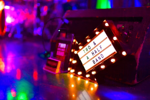 Festdekoration mit mehrfarbigen Lichtpunkten auf Konfetti und beleuchteter, umgedrehter Bühne für eine Party-Atmosphäre.