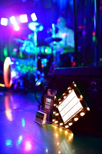 Bühnen-Showelement mit beleuchteter Licht- und Lautsprechertechnik im Hintergrund, unscharf; konzipiert für ein Fest mit Live-Musik.