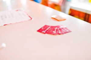 Rote Spielkarten auf einer weißen Tischfläche, mit Pfeil-Grafik und Linien im Hintergrund, wirken wie eine Kartenanwendung oder Auslage.
