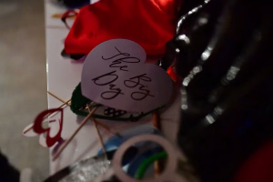 Kreisförmige Deko-Luftballonkarte mit handschriftlicher Aufschrift, im Vordergrund; rotes Tuch und unscharfer Hintergrund.