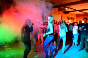 Partyraum mit Tanzenden; farbiger Nebel und Licht stimmungsvoll über die tanzenden Personen hinweg, im Hintergrund weiterer Publikum.