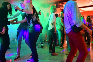 Tanzende Personen auf einer Party mit farbigem Licht, Bewegung zur Unterhaltung auf einer beleuchteten Tanzfläche.