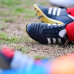 Nahaufnahme eines Sportschuhs mit Schnürung im Gras, genutzt zum Laufen und zur Demonstration von Sohlenkontakt.